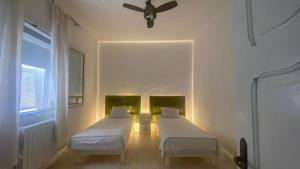 a room with two beds and a ceiling fan at Nice house ideally located in Dar Tahar Zaouch