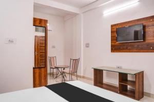 a room with a bed and a table and a tv at Super Hotel O Neelbad Guest House in Bhopal +23 photos