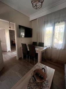 a living room with a table and chairs and a television at John and Tania's Garden in Prinos