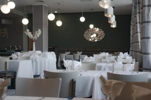 ein Esszimmer mit weißen Tischen und Stühlen und einem Kronleuchter in der Unterkunft Hotel Zenith in Oran