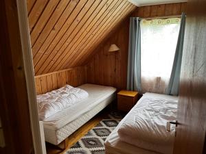 a small bedroom with two beds and a window at Enesi holiday house in Hestenesøyra