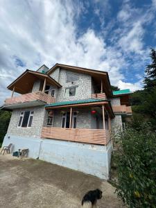 a house with a dog standing in front of it at Himalayan Whisper in Kulu