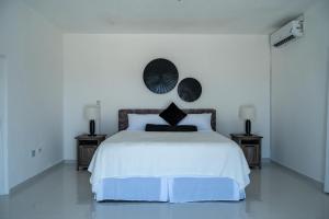 a white bedroom with a large bed with two night stands at Emotions by Ironshore in Montego Bay +39 photos