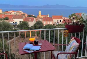 ein Tisch mit Büchern und Getränken auf einem Balkon in der Unterkunft Solacargese-Le Jardin d'Irène-Vue panoramique exceptionnelle sur la Méditerranée in Cargèse + 33 Fotos