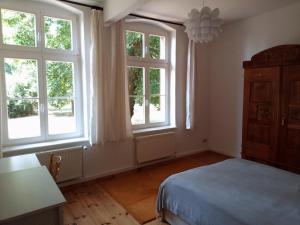 a bedroom with windows and a bed and a table at Alte Dorfschule Sacro in Sacro