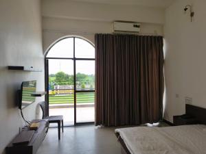 a bedroom with a bed and a large window at The Emerald Palace in Sehore