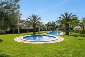 a swimming pool in a yard with palm trees at Apartment Miami Platja 80 m² Pool in Miami Platja