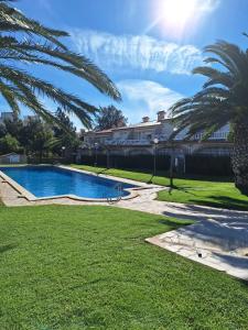 a swimming pool with palm trees and a building at Apartment Miami Platja 80 m² Pool in Miami Platja