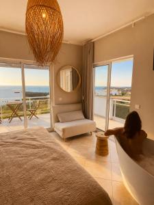 a woman sitting in a tub in a bedroom with a view at Arrifana Destination Suites in Aljezur +71 photos