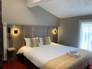 a bedroom with a large bed with white sheets and pillows at Brit Hotel Bleu Nuit in Saintes