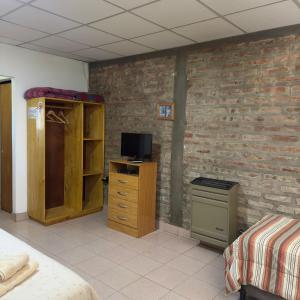 a bedroom with a brick wall with a tv and a dresser at Costa Azul 3 in Villa Pehuenia