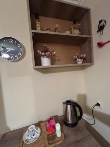 a table with a tea kettle and a clock on a wall at Guest House Panda in Kutaisi