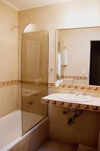 ein Badezimmer mit einem Waschbecken, einer Badewanne und einem Spiegel in der Unterkunft Hotel del Virrey in Luján