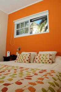 a bedroom with an orange wall and a bed with a window at Hotel del Virrey in Luján