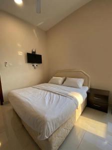 a bedroom with a white bed with a tv on the wall at RED algarbeia in Salalah +6 photos