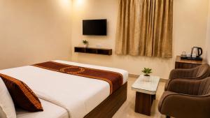 a bedroom with a bed and a tv and a chair at Hotel Namah Prime Near By Chanda Nagar Ameenpur Road in Hyderabad