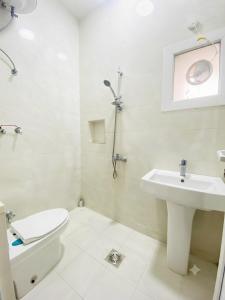 a white bathroom with a sink and a toilet at RED algarbeia in Salalah