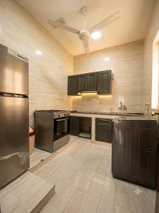 a large kitchen with black appliances and a ceiling fan at RED algarbeia in Salalah