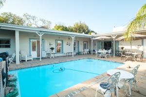 a swimming pool with chairs and tables in front of a house at Paradiso Guesthouse & Self-catering Cottage in Cape Town