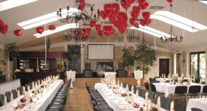 a banquet hall with white tables and chairs and red umbrellas at Gasthof Schondelmaier in Oschersleben