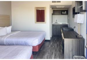 a small hotel room with two beds and a kitchen at Studio 6 Fort Collins CO in Fort Collins