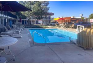 a large blue swimming pool with a table and chairs at Studio 6 Fort Collins CO in Fort Collins