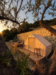 a white tent sitting next to a stone wall at Cimarte The Path Lukove in Lukovë