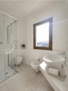 a white bathroom with a sink and a glass shower at Hotel Cala d'Oro - Hotel a pochi minuti dal mare di Cala Liberotto in Cala Liberotto