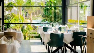 a restaurant with white tables and green chairs at Palmera Resort Wellness & Spa - Mountain & Pool View Studio 1 by Azur Prime in Vasilia
