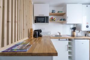 a kitchen with white cabinets and a wooden counter top at Studio cosy Allevard in Allevard