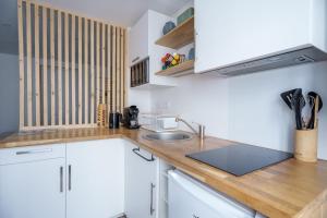a kitchen with white cabinets and a wooden counter top at Studio cosy Allevard in Allevard +4 photos