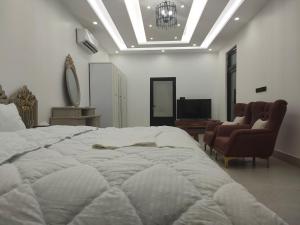a bedroom with a large bed and a couch and a chair at Alpha Holiday Home in Barka