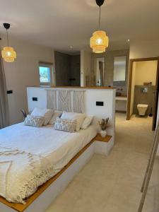 a bedroom with a large white bed and a bathroom at Monte do Raposo Country House in Monte da Pedra Alva