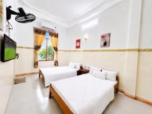 a bedroom with two beds and a flat screen tv at ĐAN MY Motel in Dong Hoi