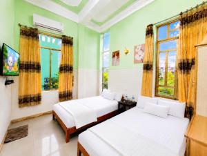 two beds in a room with two windows at ĐAN MY Motel in Dong Hoi