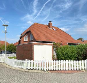 a white fence in front of a house with a white garage at Walatoll in Norden