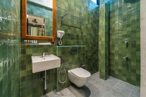 a green tiled bathroom with a toilet and a sink at Versailles Backpacker Hostel in Pondicherry