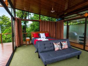a bedroom with a bed and a couch on a porch at Nido de Cristal con Jacuzzi y AC in Agua Azul