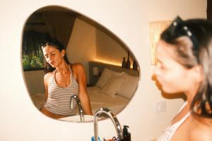 a woman looking at her reflection in a mirror at Mōmento Itamambuca in Ubatuba