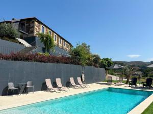 a swimming pool with chairs and a table and a building at Real Villa I by Mycelia in Real