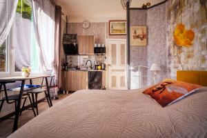 ein Schlafzimmer mit Bett und Tisch und eine Küche in der Unterkunft Studio Malou - Cosy, grande terrasse et vue rivière in Olliergues