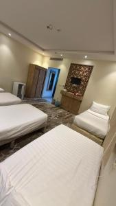 a room with three beds and a fireplace at فندق جوهرة الحجاز ريع بخش توصيل من والي الحرم مجاني in An Naqāʼ