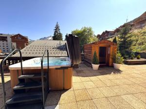a hot tub sitting on a patio with a house at Logis Hôtel Le Cairn in Les Deux Alpes