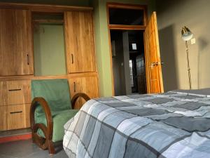 a bedroom with a bed and a green chair at Buye Holiday House in Mwanza