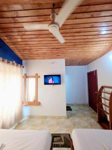 a room with a ceiling fan and a tv on a wall at Coastal daisy Beach resort in Cox's Bazar