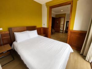 a bedroom with a white bed and a yellow wall at Cavi Rooms 304 in Cuenca