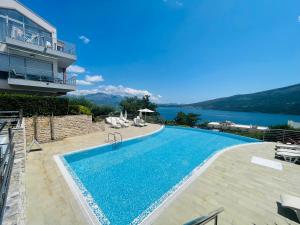 a swimming pool next to a building with a view of the water at Acacia Hill Apartment C01 with shared pool in Đenovići