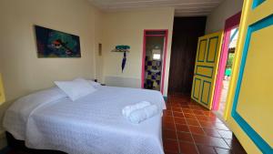 a bedroom with a white bed and a colorful door at Las Bailarinas Hotel Campestre in Montenegro