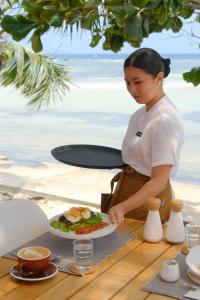 a woman standing at a table with a plate of food at Soluna Siquijor Boutique Resort in San Juan