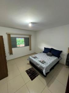 a bedroom with a bed with blue pillows and a window at Casa Carregosa in São Roque